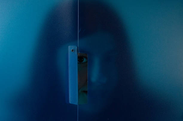 Artistic picture of a teenager with a suggestive facial expression Young woman peeking out from behind a blue transparency screen. Artistic photo. Expressive young model for advertising and social media design.