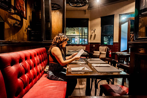 istock Young woman reading a menu at a restaurant 2234541339