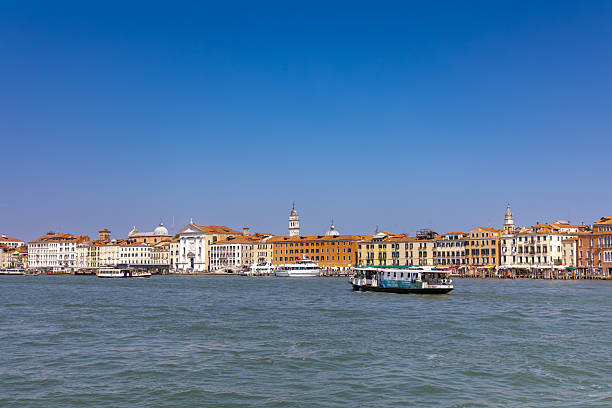 Venice, Italy, August 11, 2025:  Scenic view of Venice waterfront with historic buildings and boats on the Grand Canal under a clear blue sky.