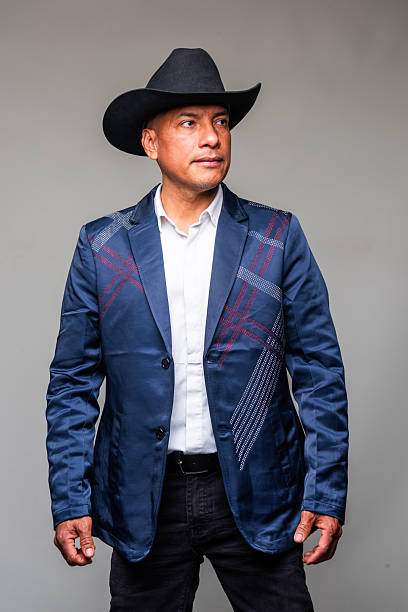 istock Hispanic man wearing a jacket and a cowboy hat looking at the camera on gray background 2234542613