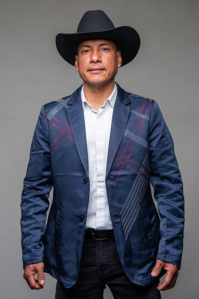 istock Hispanic man wearing a jacket and a cowboy hat looking at the camera on gray background 2234542614