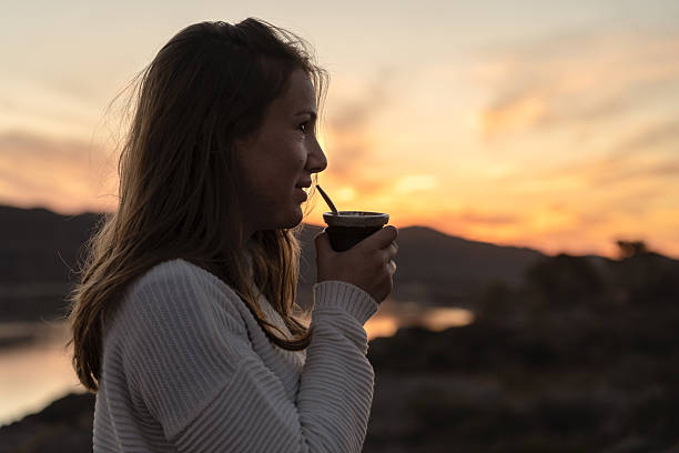istock Young woman drinking mate during sunset in natural outdoor setting 2234545381