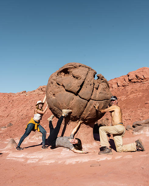 istock Tourists posing with large rock formation in desert landscape 2234545707