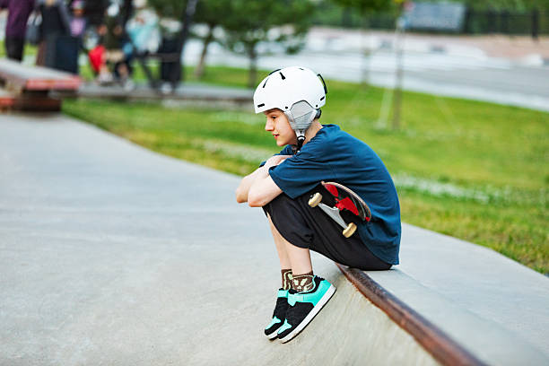 Boy in crash helmet skateboards in park, enjoying in sunny sunny day