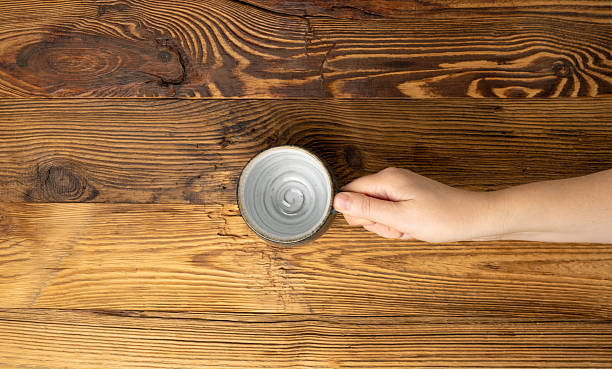 istock Hand Holds Cup, Empty Cup in Hands, Coffee Mug, Teacup Mockup, Cup in Arms on Wooden Table 2234549335