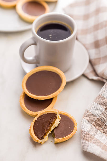 istock Sweet chocolate tartelettes and coffee cup on white table. 2234549490