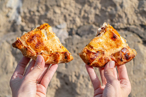 Two slices of pizza hold in the woman's hands with stone background, Gozo, Malta