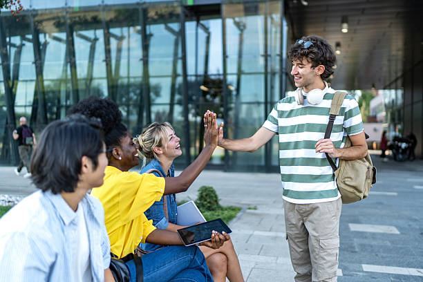 Group of multi-ethnic university students celebrating outdoors, joyfully giving high fives after passing their exam, sharing smiles and laughter in a moment of achievement and friendship