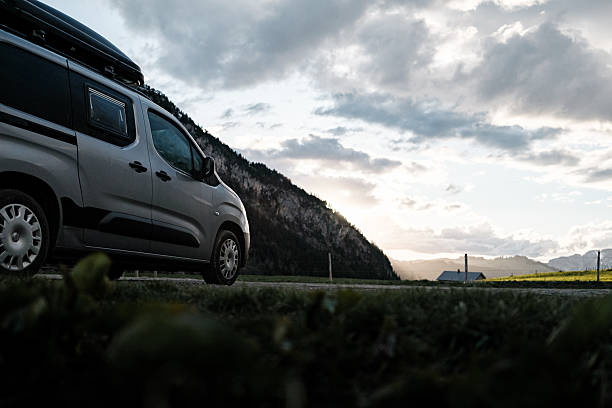 Car camping in meadow at sunrise, distant mountains and storm, Col des Aravis