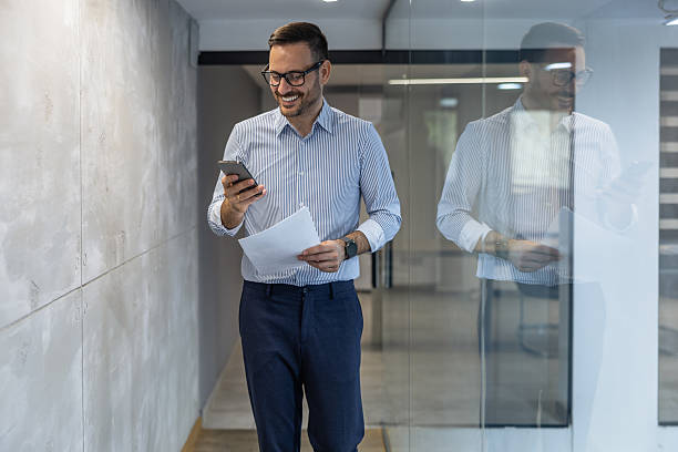 istock Business professional walking with smartphone and documents in modern office hallway during daytime 2234551246