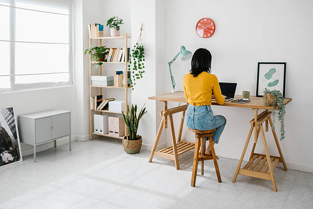 istock Rear view of young woman sitting on a workplace while working from home. 2234552550