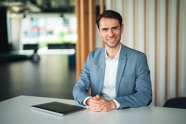 istock Thoughtful business man sitting on a desk and smiling 2234552614