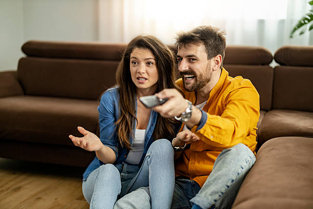 istock Couple enjoying movie night at home with remote control and comfortable seating while sharing laughs and snacks 2234553338
