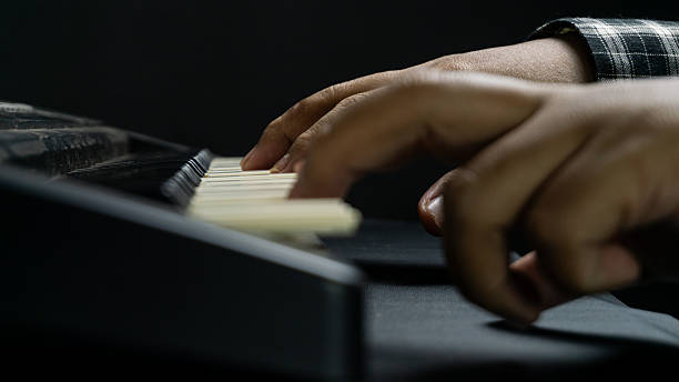 istock Close up of piano being played with both hands from direct side view, dark background and instrument tones, concept of classical music, performance, and harmony. 2234553369