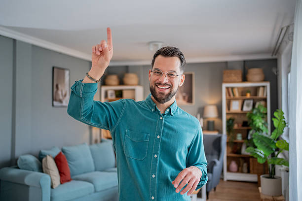 istock Young man pointing upwards and smiling in living room 2234556762