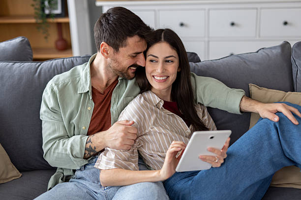 istock Happy Couple Laughing While Browsing Together on a Tablet 2234570944