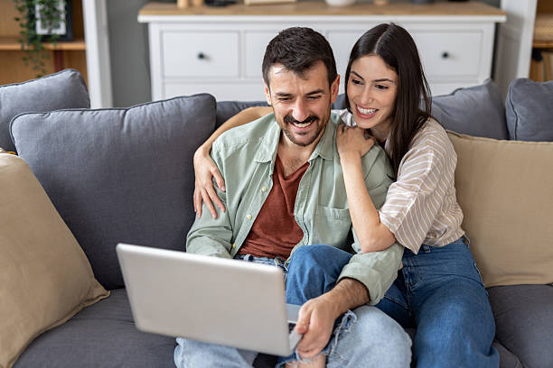 istock Loving Couple Smiling Together While Looking at Laptop 2234570945