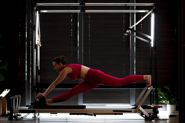 istock Fitness enthusiast practices stretching routine on reformer equipment in modern studio during evening workout session 2234571295
