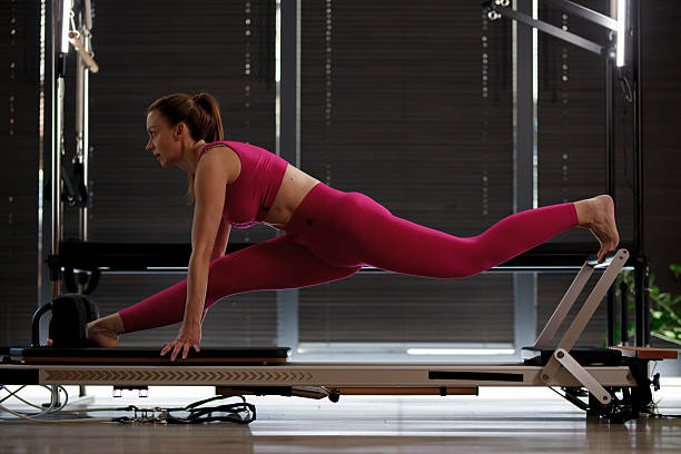 istock Fitness enthusiast performs an agile stretch on a reformer machine in a well-lit studio space during a morning workout session 2234571450