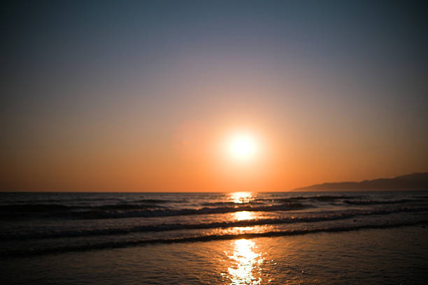 Illuminating sunset reflecting vibrant colors on the calm waters at Venice Beach, with gentle waves rolling in.