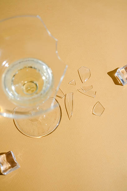 istock Broken glass cup with liquid and ice cubes scattered on a light brown surface 2234572610