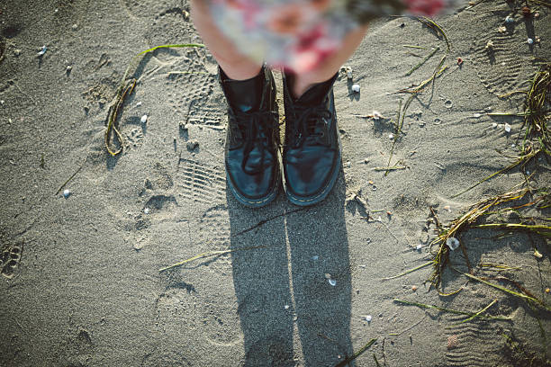Lifestyle pictures of a young brunette woman with a flower dress walking on the beach at dusk.