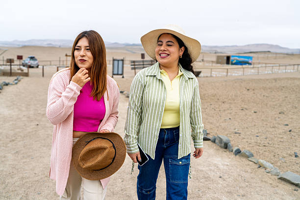 Two young women walking and chatting while discovering the ancient pre-inca ruins nestled in a stunning coastal desert landscape