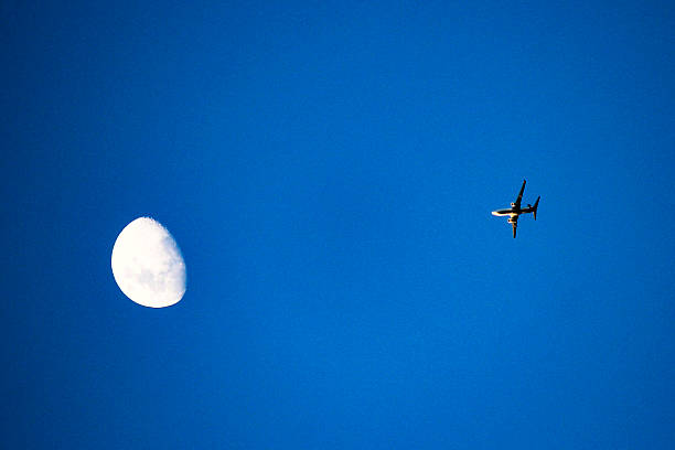 istock A plane flies past the moon in a clear blue sky 2234596031