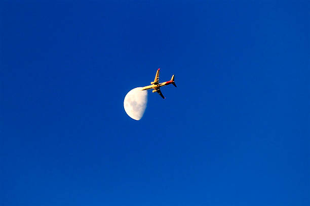 istock A plane soars past the crescent moon in a clear blue sky 2234596046