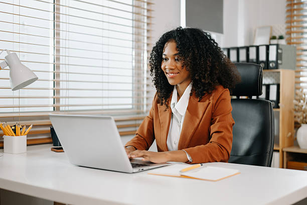 istock Young beautiful woman typing on tablet and laptop while sitting at the working white table 2234599752