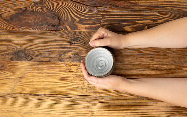 istock Hand Holds Cup, Empty Cup in Hands, Coffee Mug, Teacup Mockup, Cup in Arms on Wooden Table 2234602692