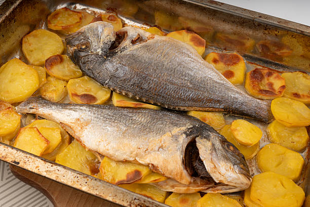 istock Dorado fish on a baking sheet with potatoes. Whole roasted seabream, gilt-head bream 2234603331
