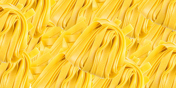 Raw yellow italian pasta pappardelle pattern, fettuccine or tagliatelle wallpaper