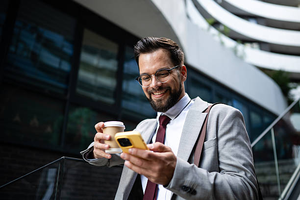 istock Happy businessman using smartphone and drinking coffee outdoors 2234606103