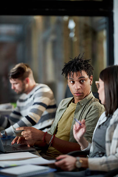 istock Black creative man using laptop and talking to his colleague in the office. 2234608593