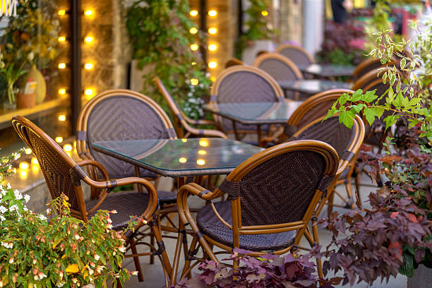istock A cafe with wicker chairs and glass tables is decorated with greenery and soft vertical lighting. 2234610374
