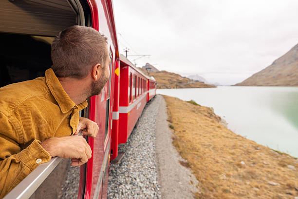 istock Man Enjoying Scenic Train Ride by Mountain Lake 2234610980