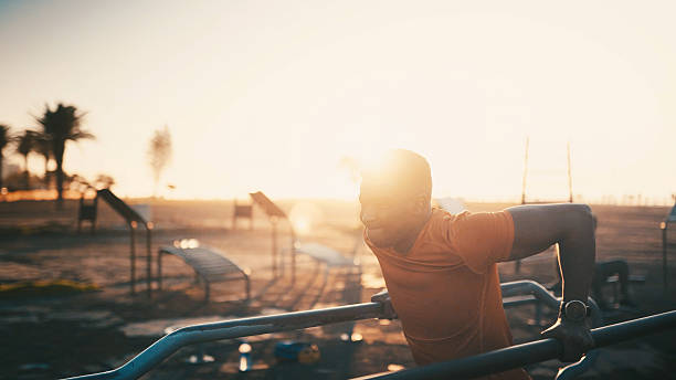 istock Athlete, black man and pull up on machine outdoor for fitness, exercise and strength training. Male person, lens flare and weightlifting with equipment, sports workout and performance for wellness 2234612634
