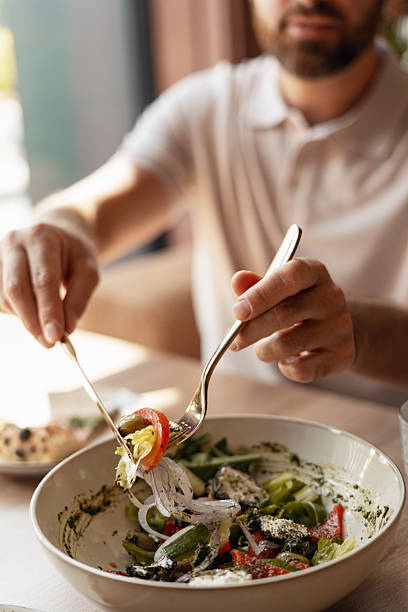 istock Man eating fresh salad in a restaurant 2234615505