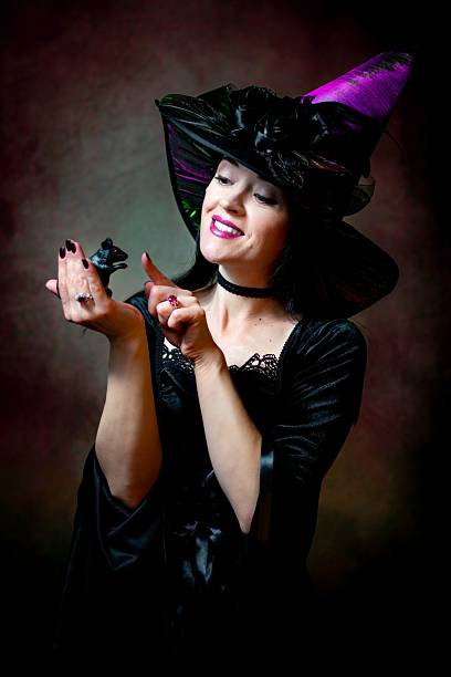 A young witch with jack o'lantern in a night misty forest. Smiling attractive woman with a carved pumpkin and smoke. Halloween party, trick or treat concept. Magic, witchcraft, sorcery. Banner with copy space