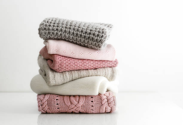 istock Stack of woolen knitted folded sweaters, warm winter autumn clothing stacked on white table. 2234629301