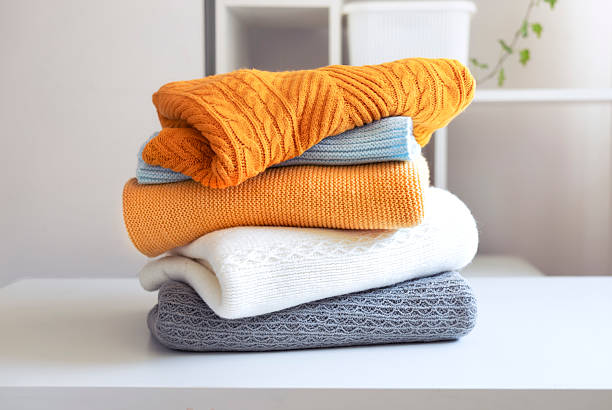 Stack of knitted folded clothes on table.Knittings pile.Autumn clothing heap.Woolen sweaters.Objects.Nobody.