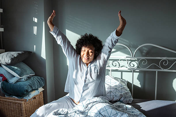 istock Woman stretching in bed while enjoying the morning sunlight 2234629510