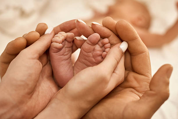 istock Newborn Baby Feet in Parent's Hands 2234630054