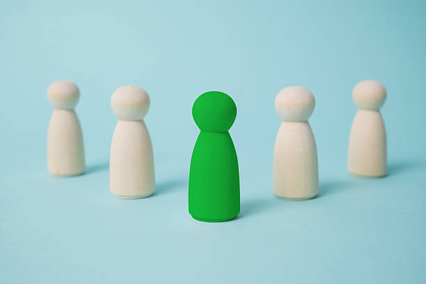 istock Green leads others from other wooden dolls on blue background. 2234635582