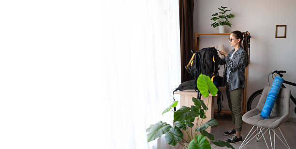 Hiker preparing for hiking trip packing backpack for hike at home indoors. banner, copy space