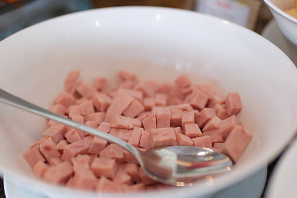 cooked sausage mortadella cubes on white background with spoon plate