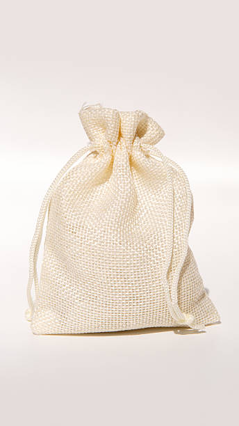 istock Beige burlap gift bag with drawstring tied on neutral background 2234639450
