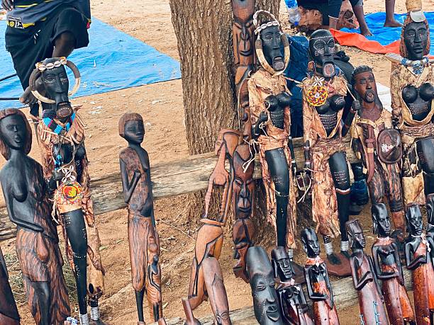 Collection of Ethiopian wooden figurines dressed in traditional attire with beadwork, handmade and sold at Turmi handicrafts market.