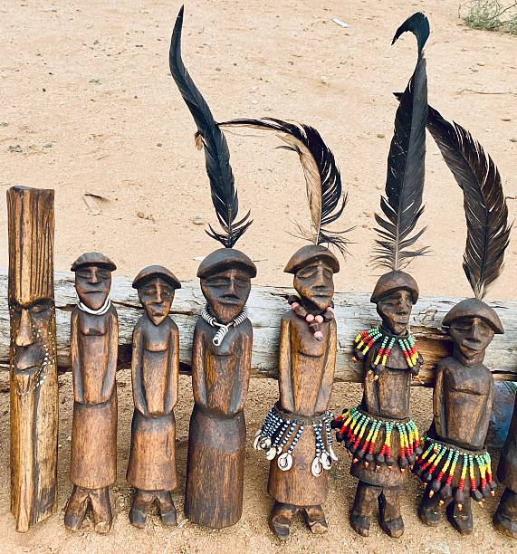 Group of hand-carved Ethiopian wooden figurines, some adorned with beads and feathers, displayed for sale at the Turmi handicrafts market.